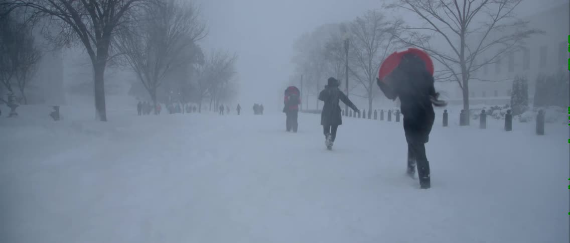 People walk along a long road in the heavy snow