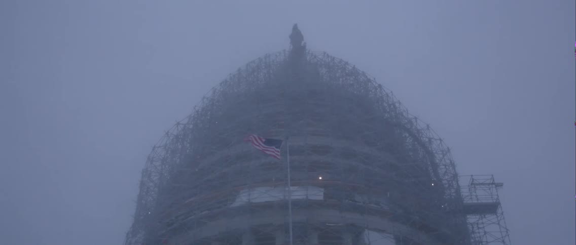 A view of a building and a flag as it blows in the snow