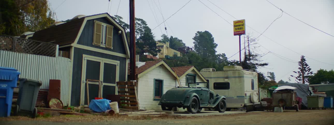 Vintage car sits parked near general store near dirt road
