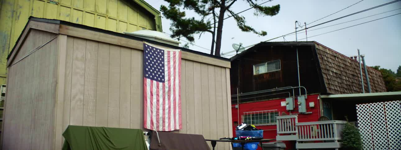 A shed and a few buildings close to each the shed has an american flag