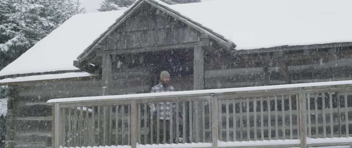 Man walks on porch as the snow falls