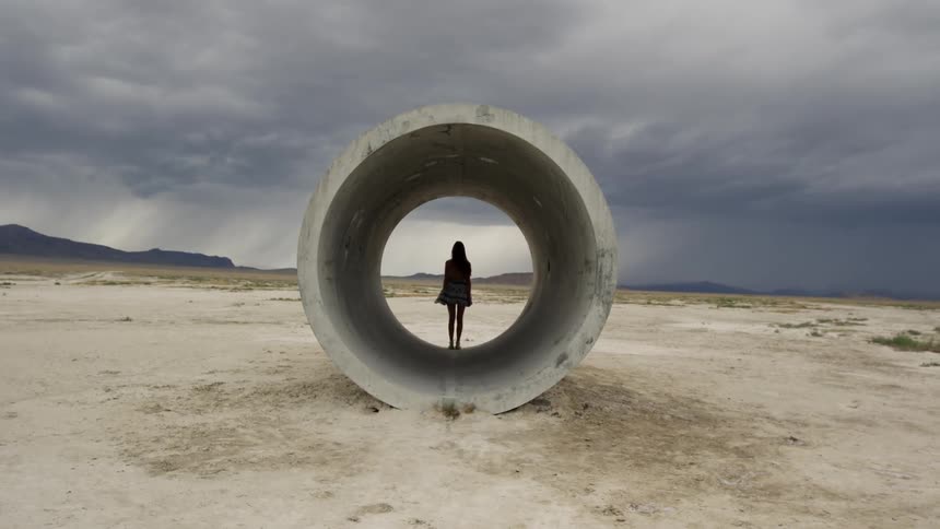 A woman stands in a concrete pipe