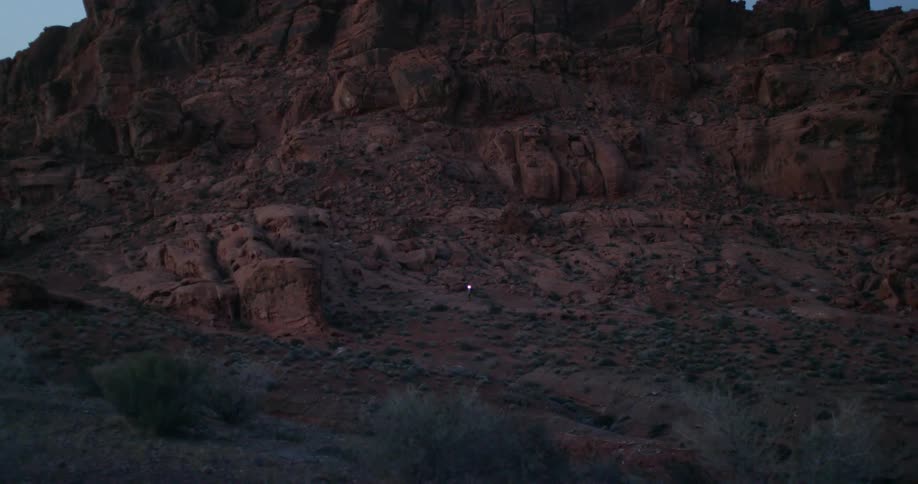 A person is climbing down from the rocks in the distance