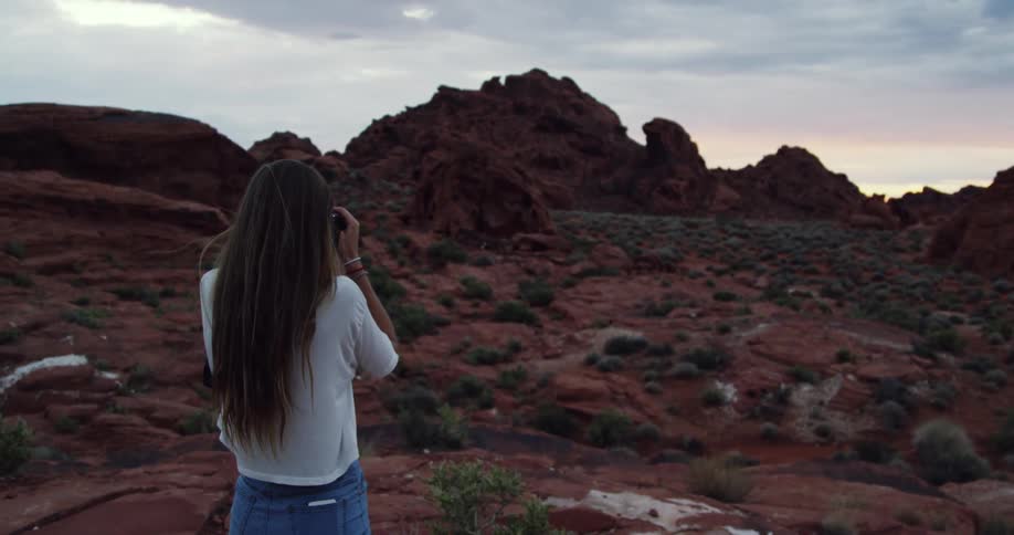 Woman takes pictures of a rocky landscape on a cloudy day