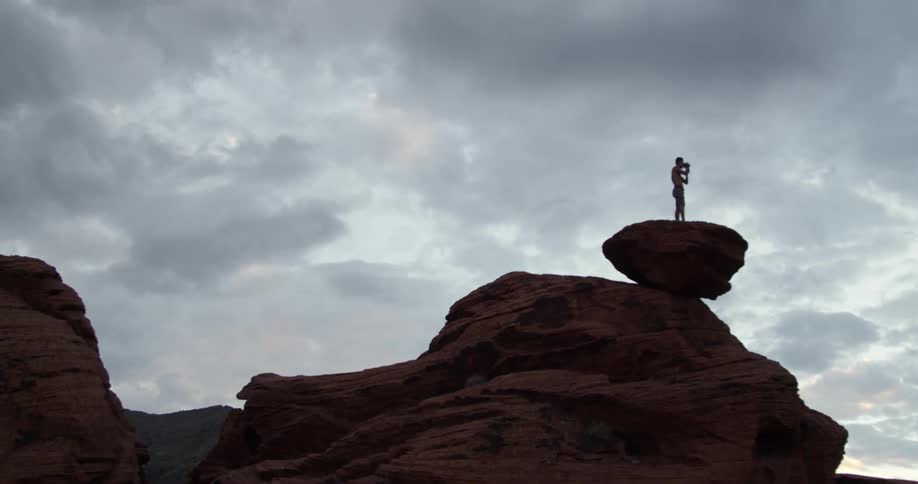 A man is standing on the top of a pile or rocks