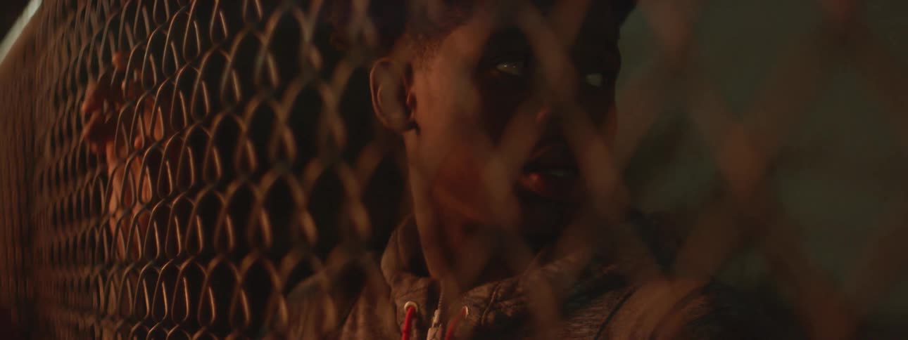 A young man looks through a fence