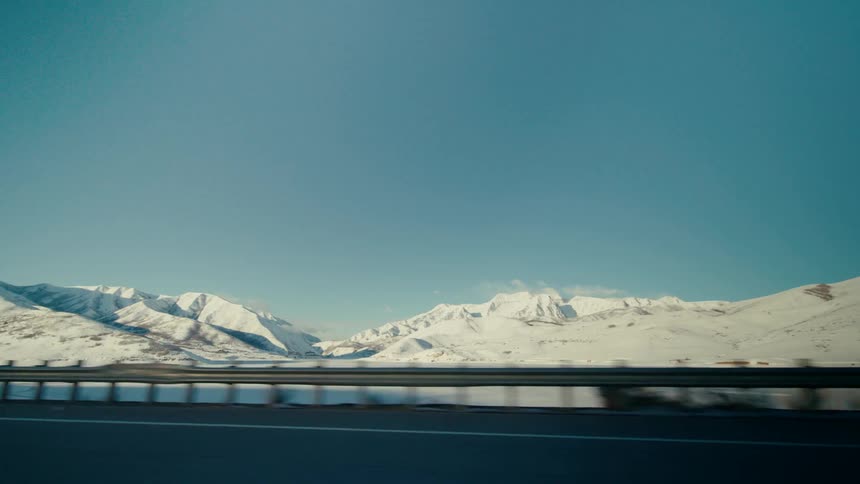 Traveling along highway with view of snowcovered terrain and mountains during the day