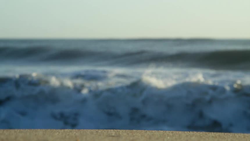 Waves in the ocean roll and crash against the sandy beach