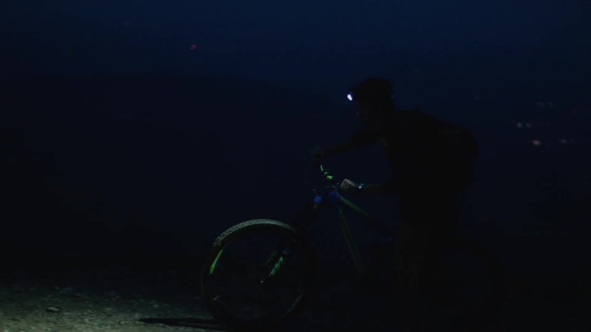 The view is of a man riding his bike in the dark