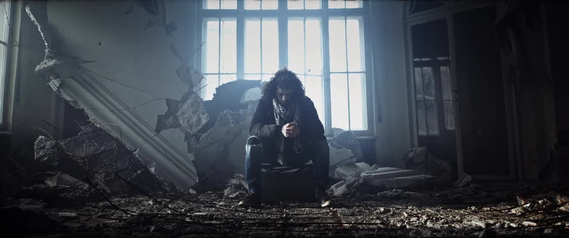 The view is of a young man sitting inside of a house