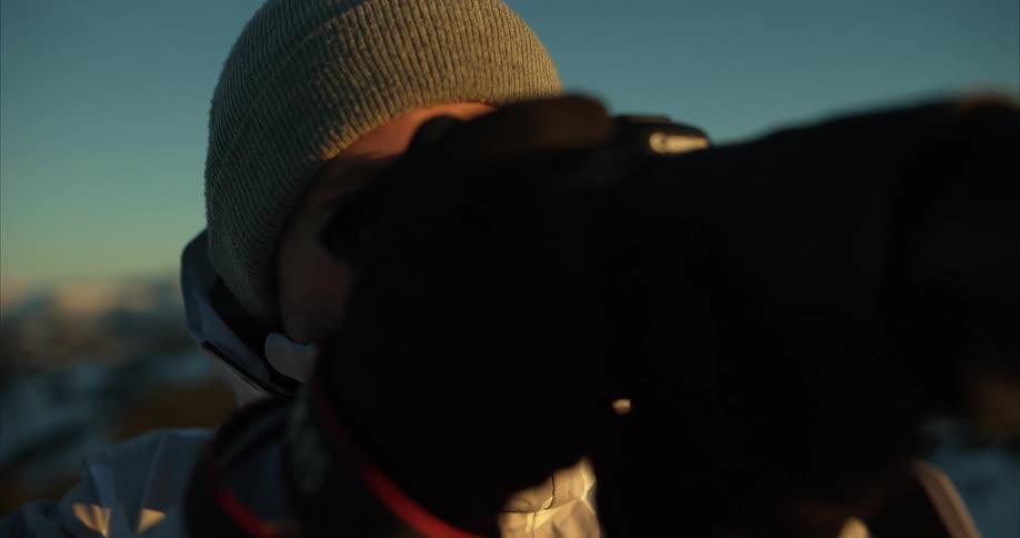 A man takes photos while standing on snow capped mountains