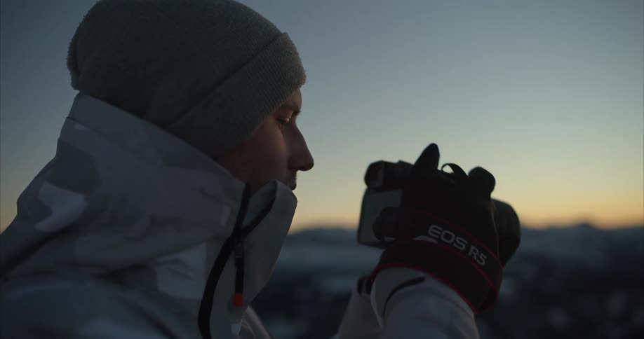 A man is taking pictures of the horizon at dusk