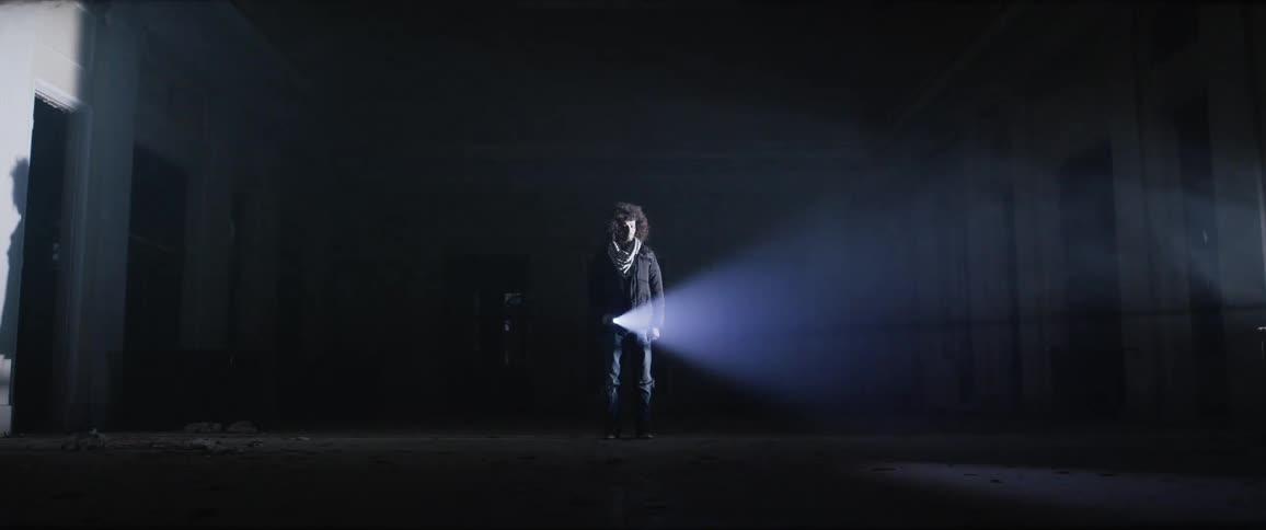 Man standing in empty house in the dark moving a flashlight around cashing shadows and light moving everywhere