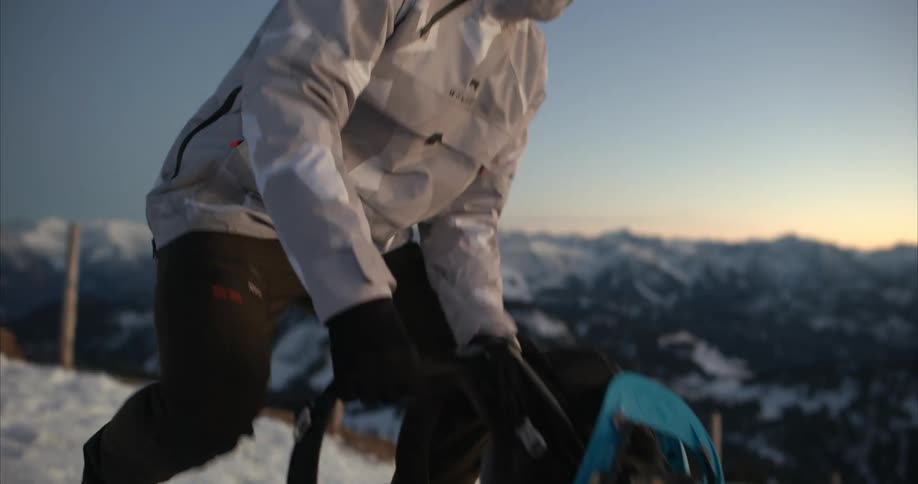 A backpacker stops on a snowy mountain to get out his camera