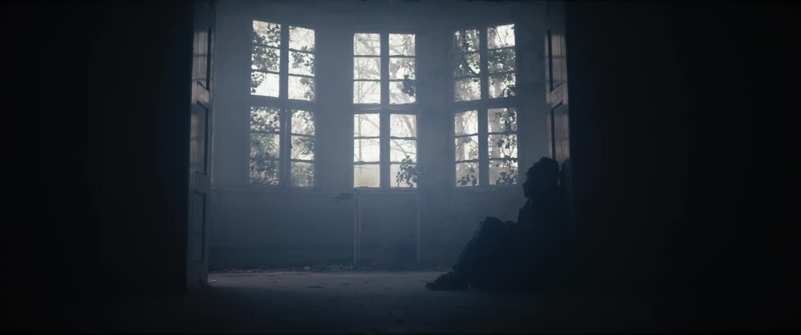 A man in sitting down on the floor inside of a house