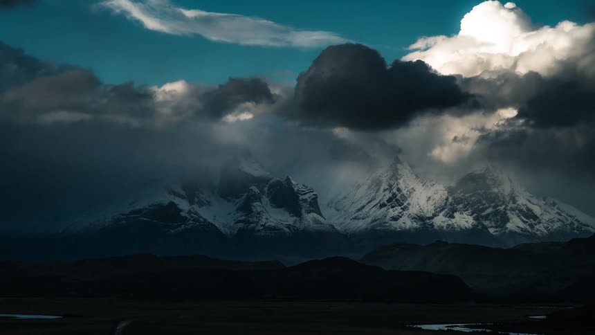 Dark clouds move over snow capped mountains