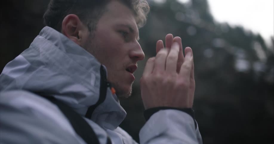 A young man is outdoors and is cold as he tries to warm up