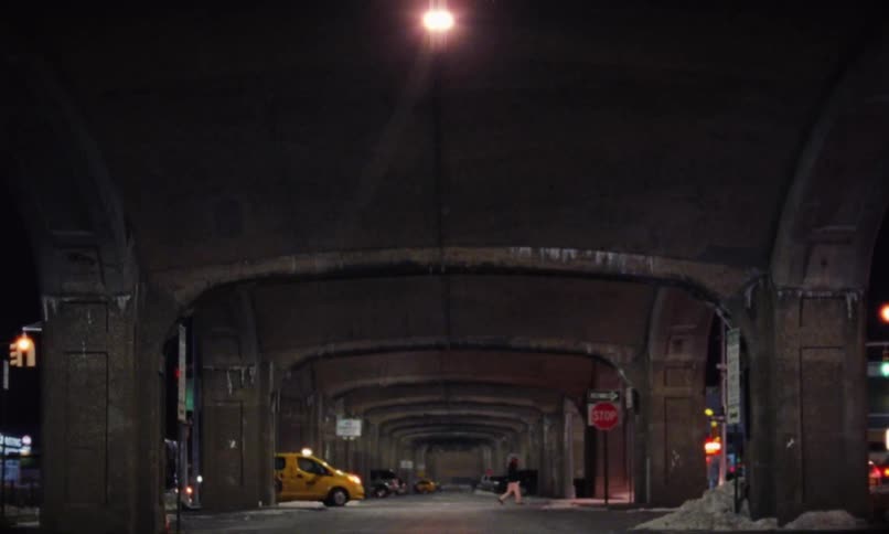 Nighttime view from under freeway underpass with people and cars