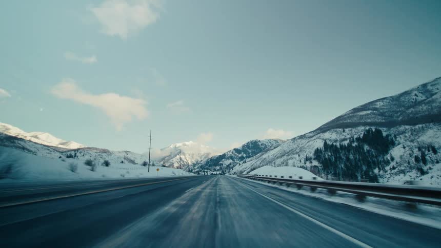 Vehicle drives on highway near the snowy mountain slopes