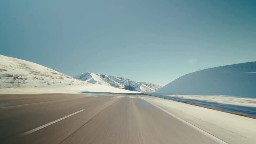 A highway runs past snow covered mountains