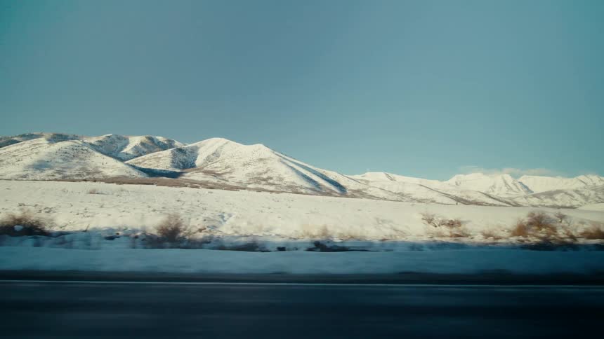 A highway runs along snow covered mountains