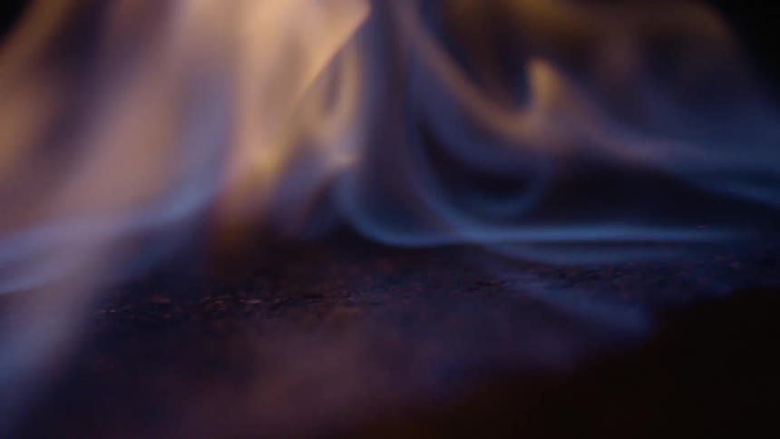 Blue flames rise and waver as they burn in the darkness