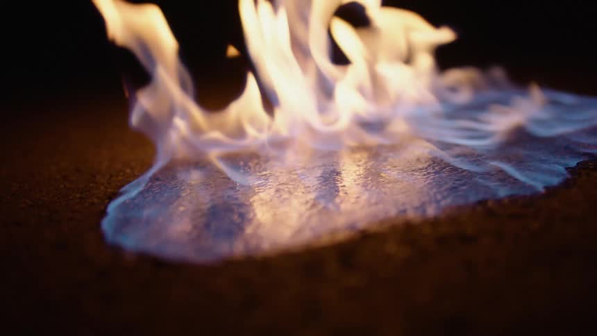 Close up of blue and yellow flames over concrete at night
