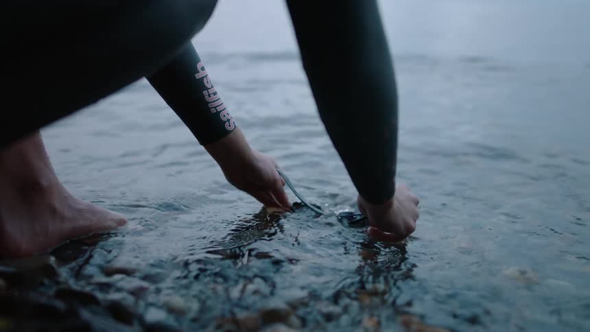 A person is rinsing off their goggles in a body of water
