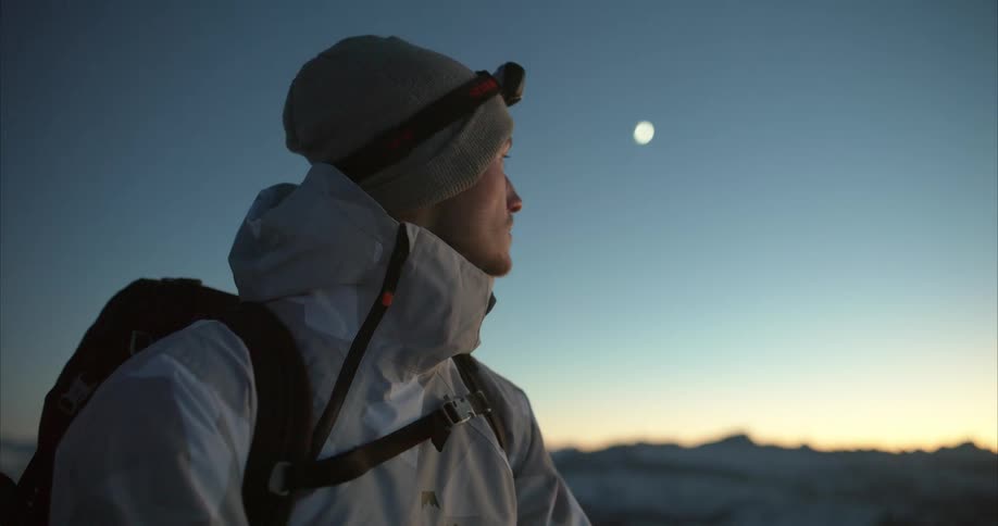 A man takes in the view while standing on snow covered mountains