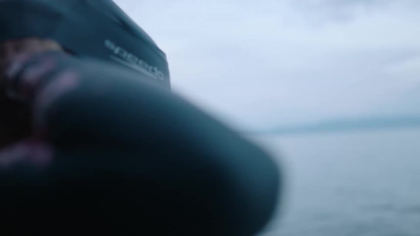 A woman looking out over a body of water puts on a swimming cap