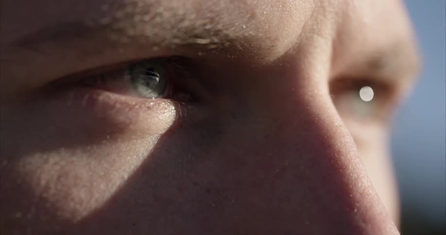 An extreme close up of a mans eyes as he lifts something in front of them