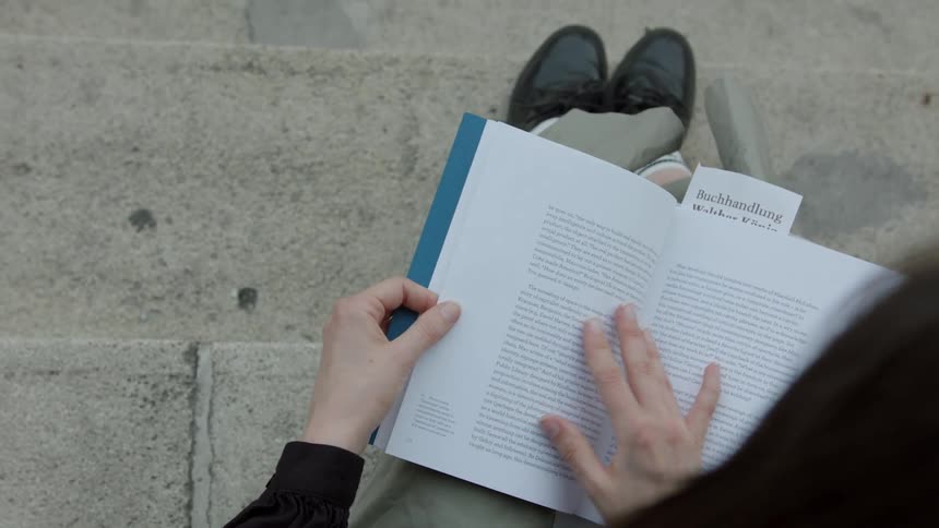 A person is sitting on steps and reading a book