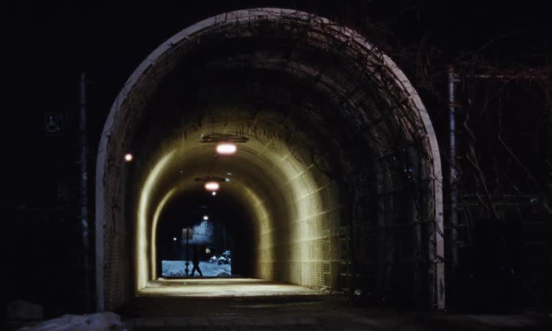 A person is walking near a tunnel in a city
