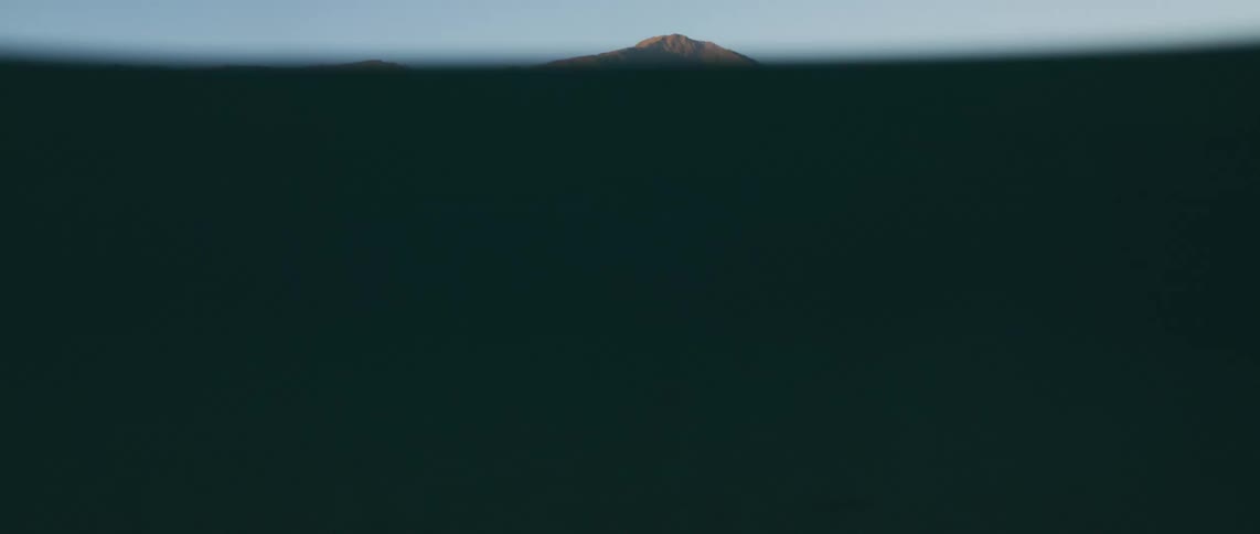 Sunlight shines on the mountains and reflects on the water as it wavers and moves to an underwater view