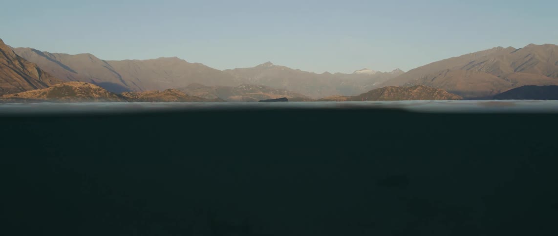 An ocean near a mountain range is displayed