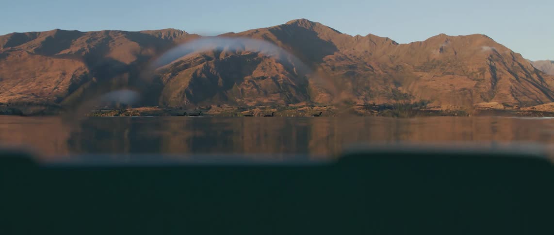 Sunlight shines on the mountains and reflects on the water as it wavers and moves to and from an underwater view