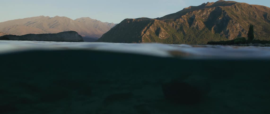 Sunlight shines on the mountains and reflects on the water as it wavers and there is also an underwater view