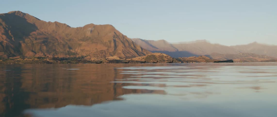 Water dries off lens allowing view of ducks in water near mountains on shore