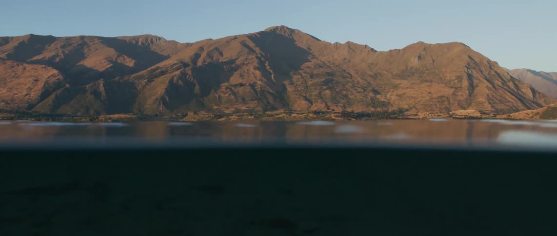 An extreme close up of the surface of water with mountains at the coast line
