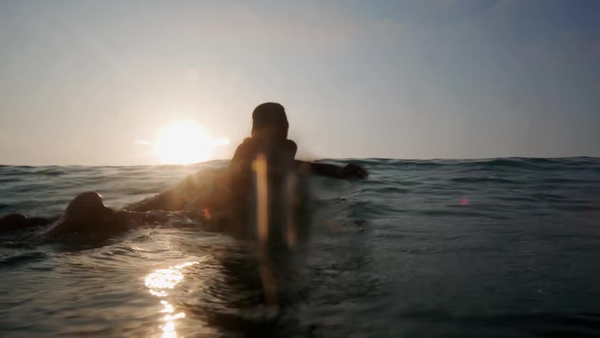 The view is of a young woman that is surfing on the ocean