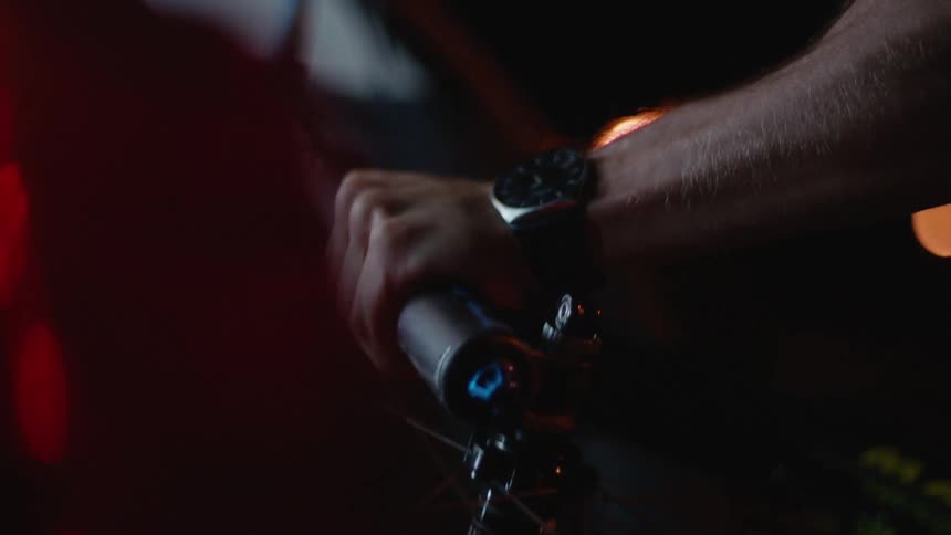 A man is holding his bike outdoors at night