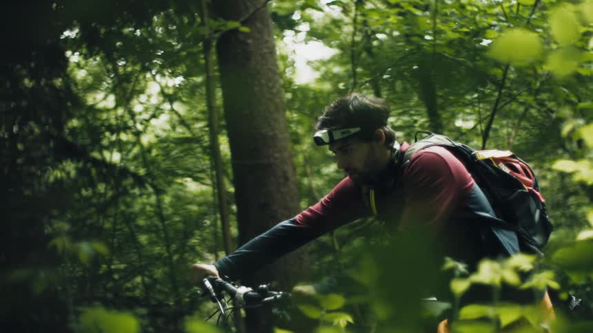 A man is riding his bike through a wooded area