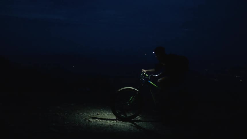 A man is biking by himself outdoors at night