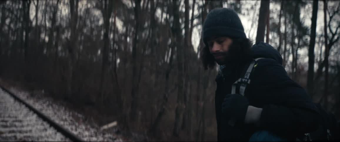 The view is of a man that is walking outside in the nature area