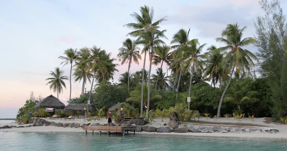 Huts and palm trees line the shore ahead