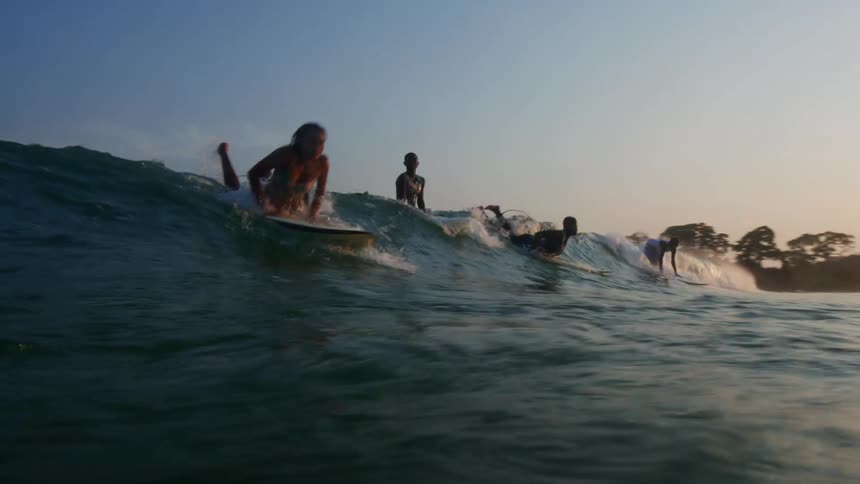 A group of women surf atop a wave together