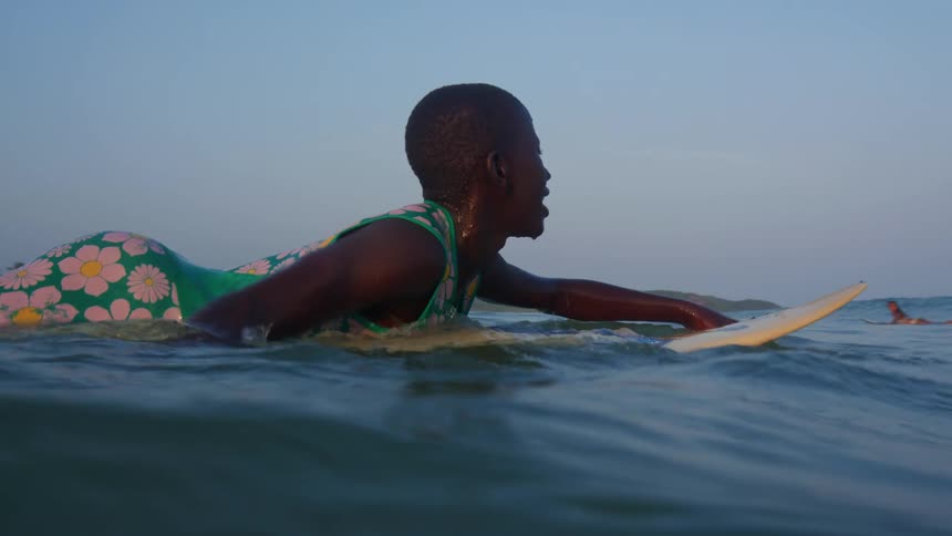 A boy is surfing in the ocean water during midday