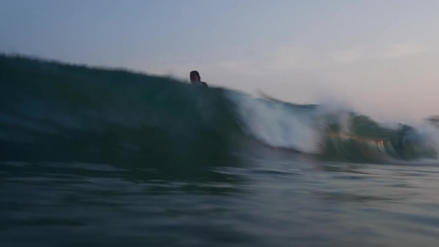 Time lapse of children riding wave on surfboards at sunset