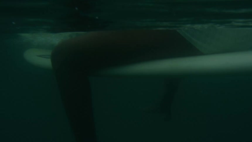 Woman in white bikini sits on surfboard