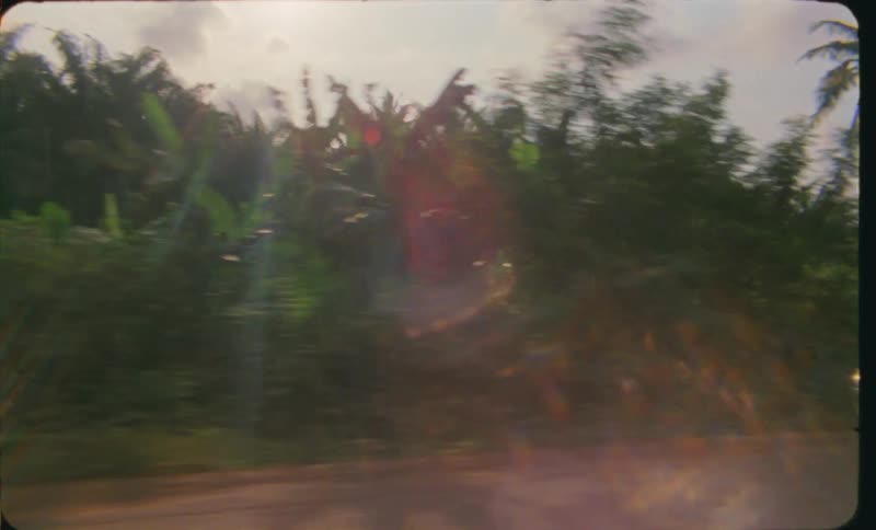 A couple of taxis driving on a dirt road on a tropical landscape caught on vintage film
